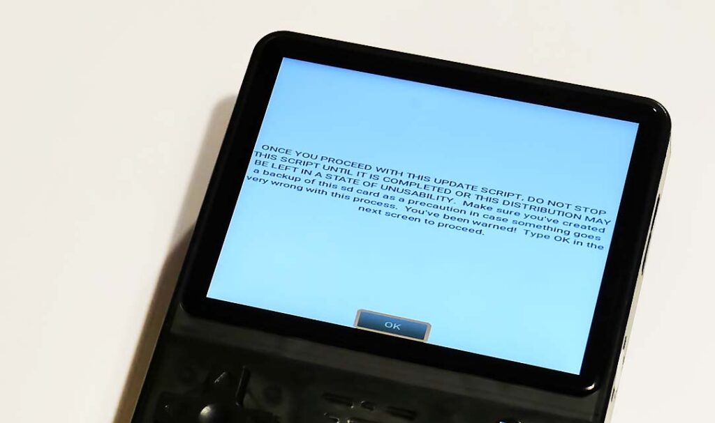 The ArkOS system update warning on the handheld emulator console screen.