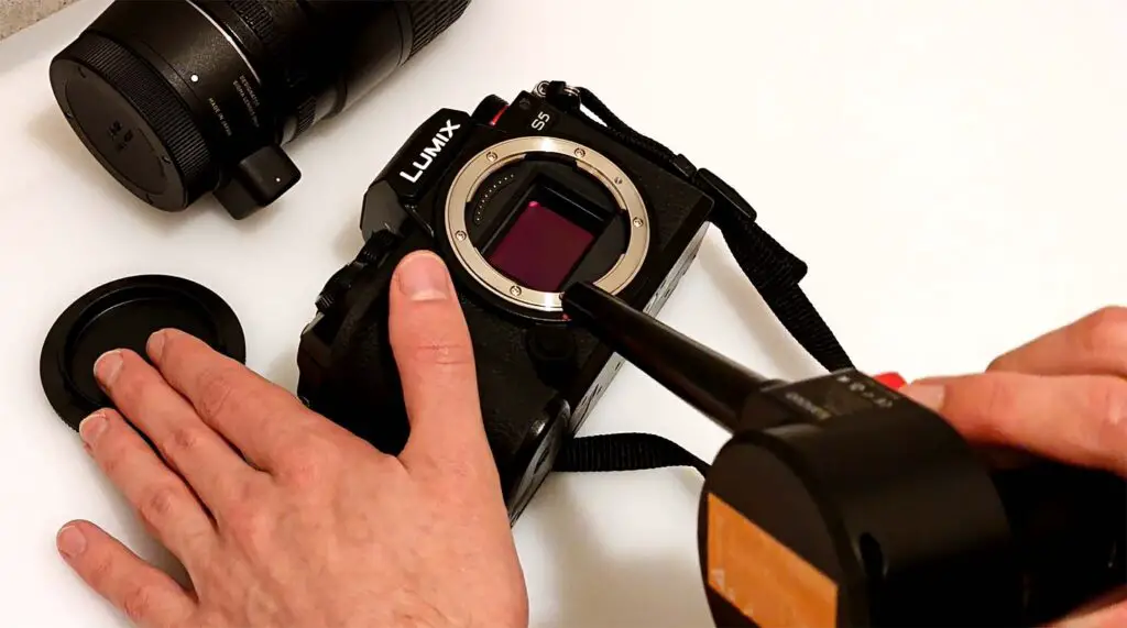 Using an air blower to remove the largest dust and dirt particles from the camera's sensor.