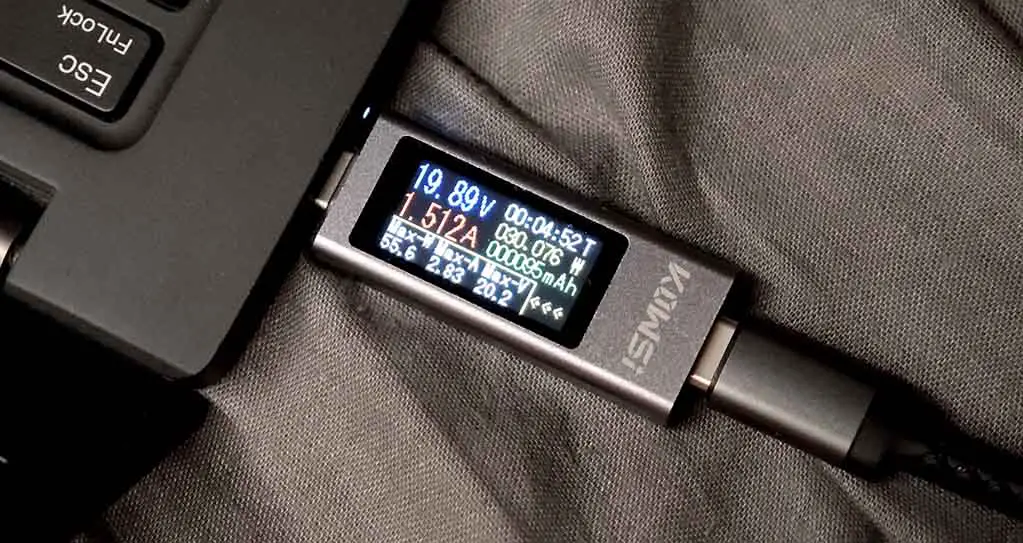A USB power meter showing the power bank delivering approximately 30W (19.89V at 1.512A) to a laptop, with a max. power output of 55.6W.