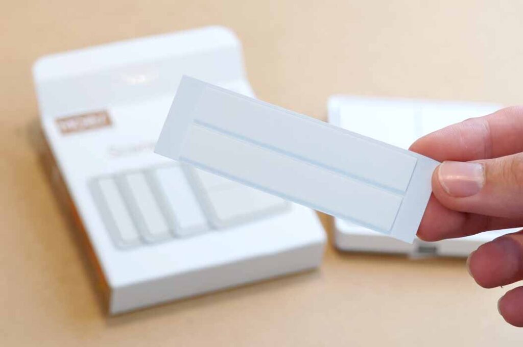 Two adhesive strips that come bundled with the button.