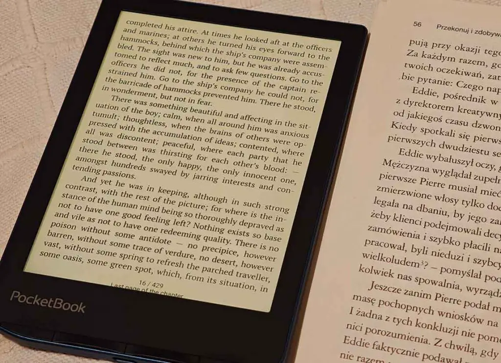 PocketBook Verse Pro next to a printed paper book with warm frontlight enabled for comparison
