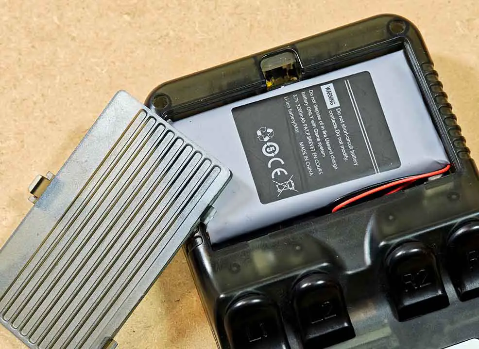 Opened R36S battery compartment showing the internal battery and connection cable.